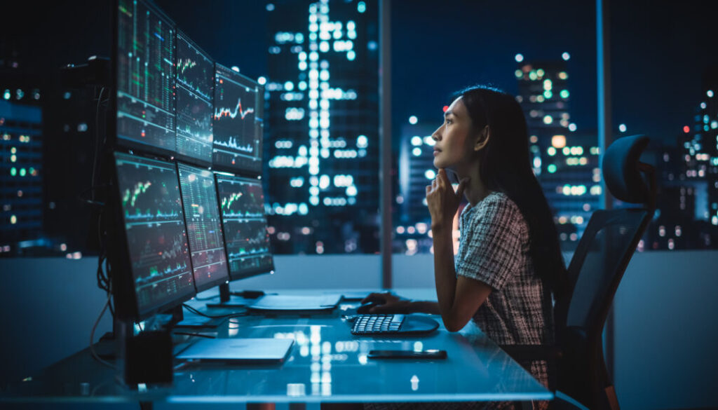 Portrait of a Financial Analyst Working on Computer with Multi-Monitor Workstation with Real-Time Stocks, Commodities and Exchange Market Charts. Businesswoman at Work in Investment Broker Agency. Portrait of a Financial Analyst Working on Computer with Multi-Monitor Workstation with Real-Time Stocks, Commodities and Exchange Market Charts. Businesswoman at Work in Investment Broker Agency.