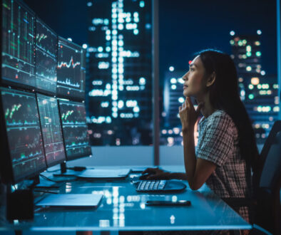 Portrait of a Financial Analyst Working on Computer with Multi-Monitor Workstation with Real-Time Stocks, Commodities and Exchange Market Charts. Businesswoman at Work in Investment Broker Agency.